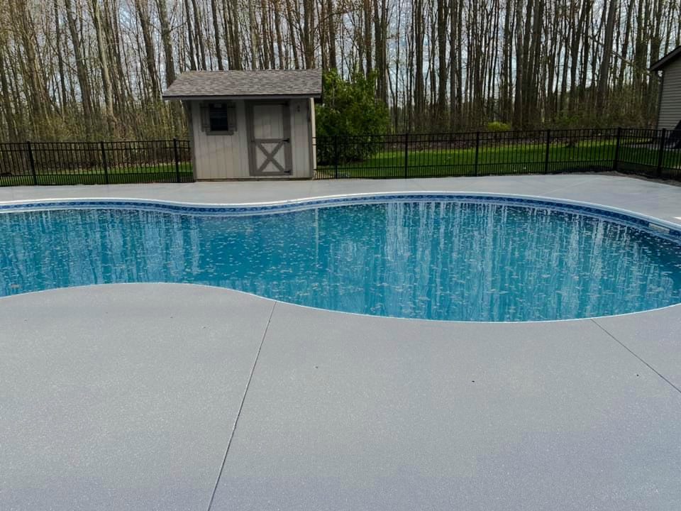 Textured coated pool deck beside a backyard pool