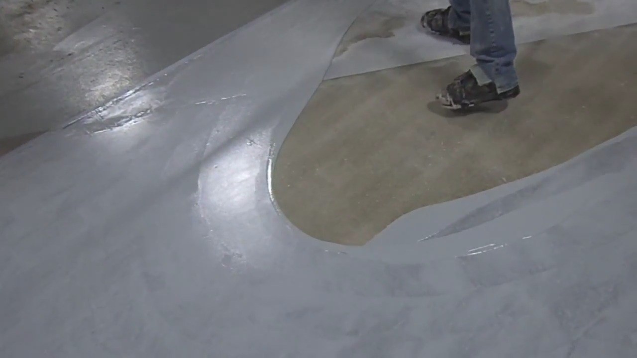 Installer in spiked shoes rolling out an epoxy floor coating
